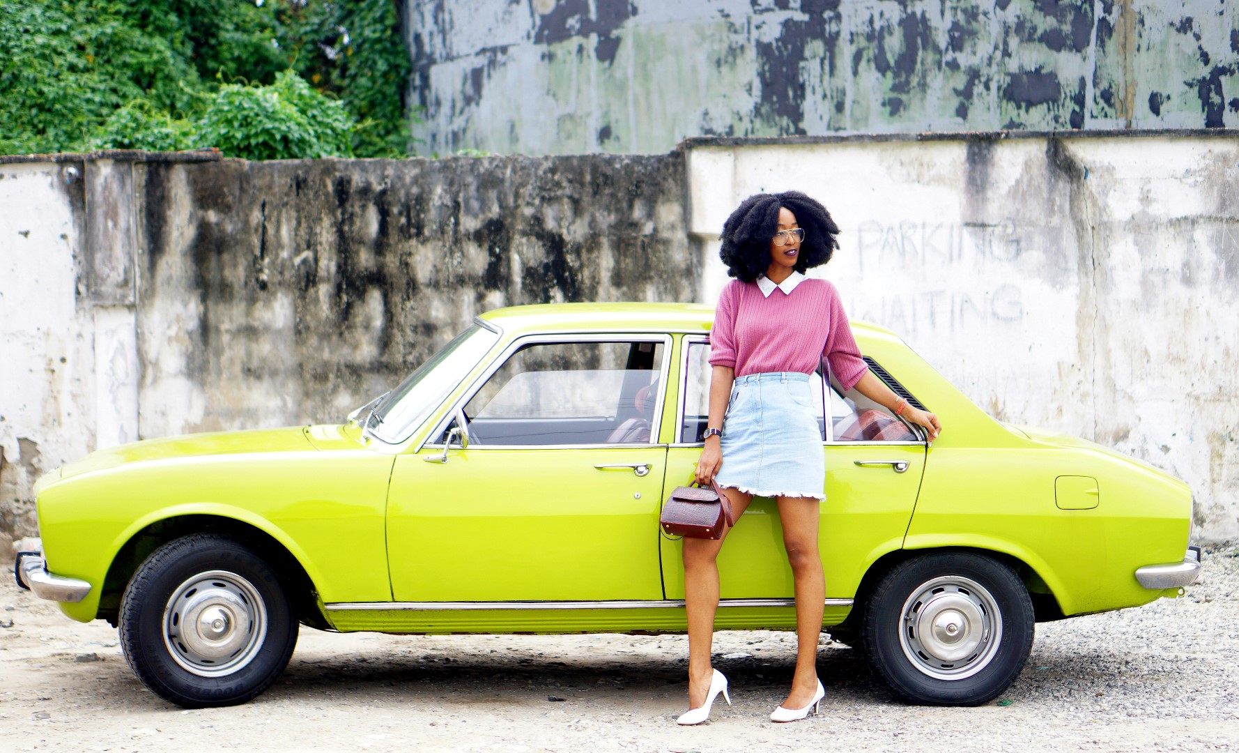 nigerian fashion blogger Cassie daves wearing a denim mini skirt. leaning against a lemon green peugeot 504