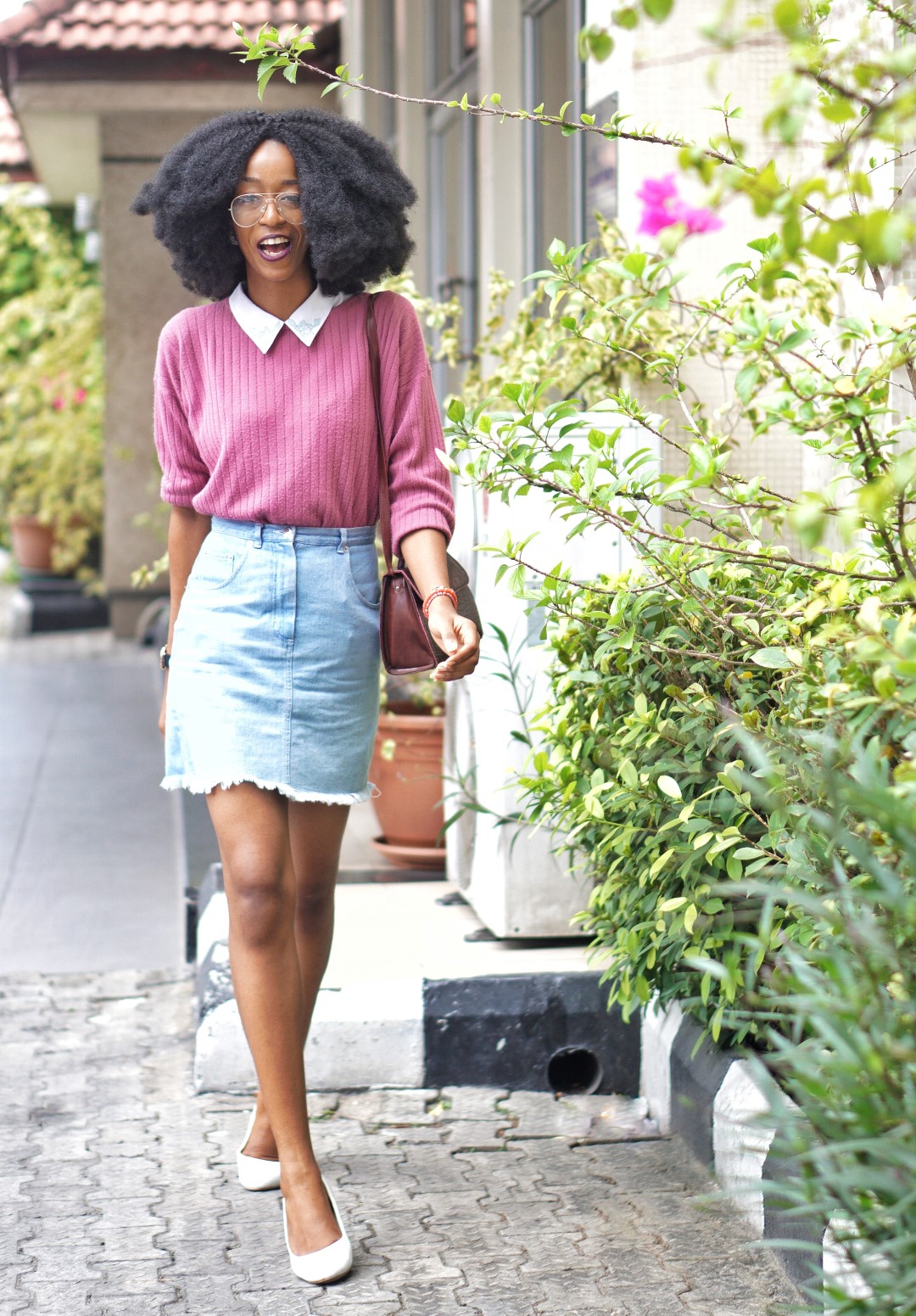 nigerian fashion blogger Cassie daves sporting a big afro, denim mini skirt, and white court shoes