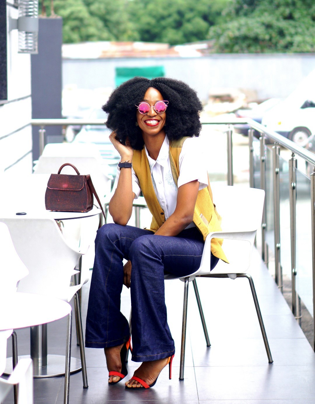 Nigerian Fashion blogger Cassie Daves in a high waisted flare jeans, mustard waist coat and white shirt 