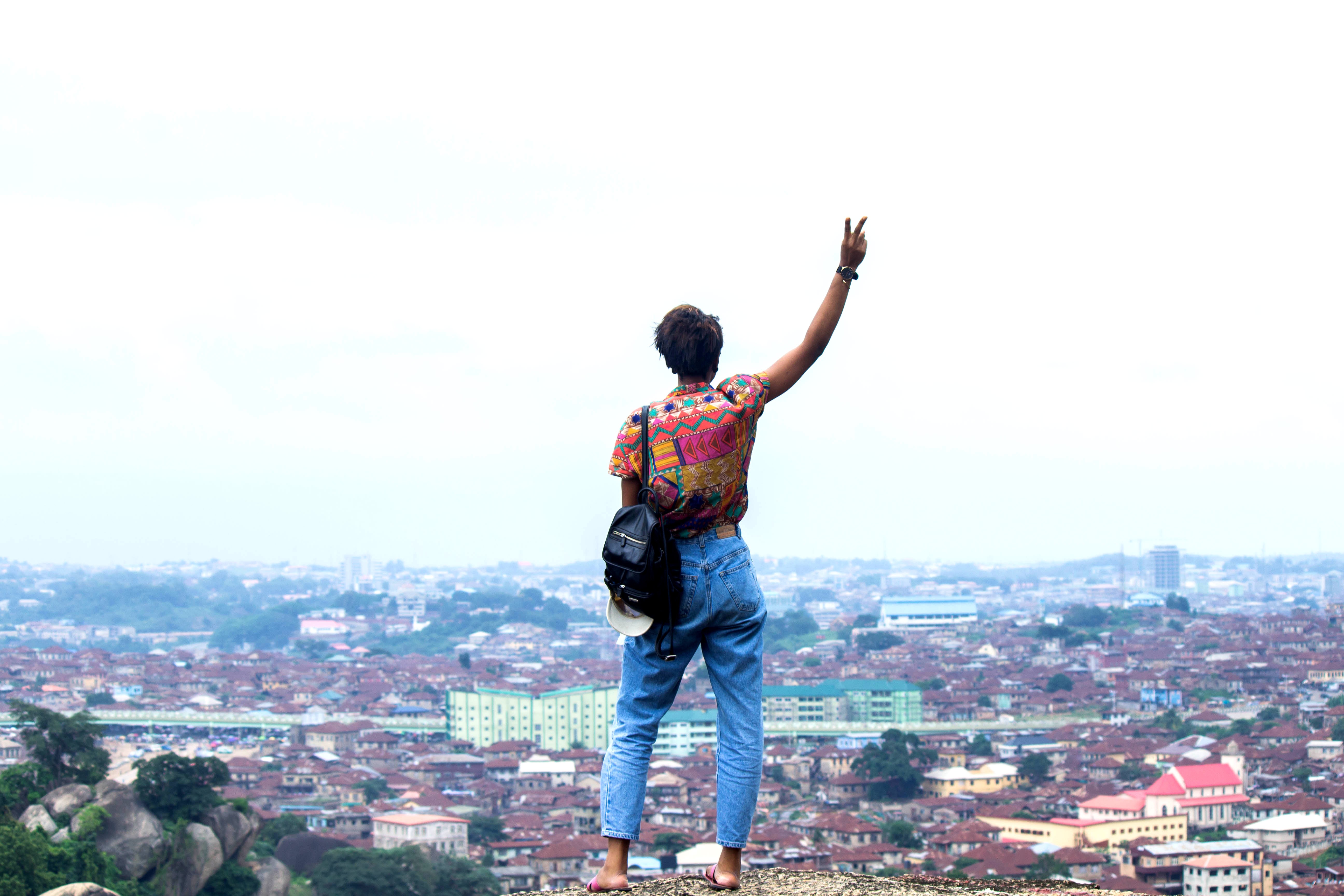 Nigerian lifestyle blogger Cassie Daves standing on the olumo rock in Abeokuta giving a peace sign
