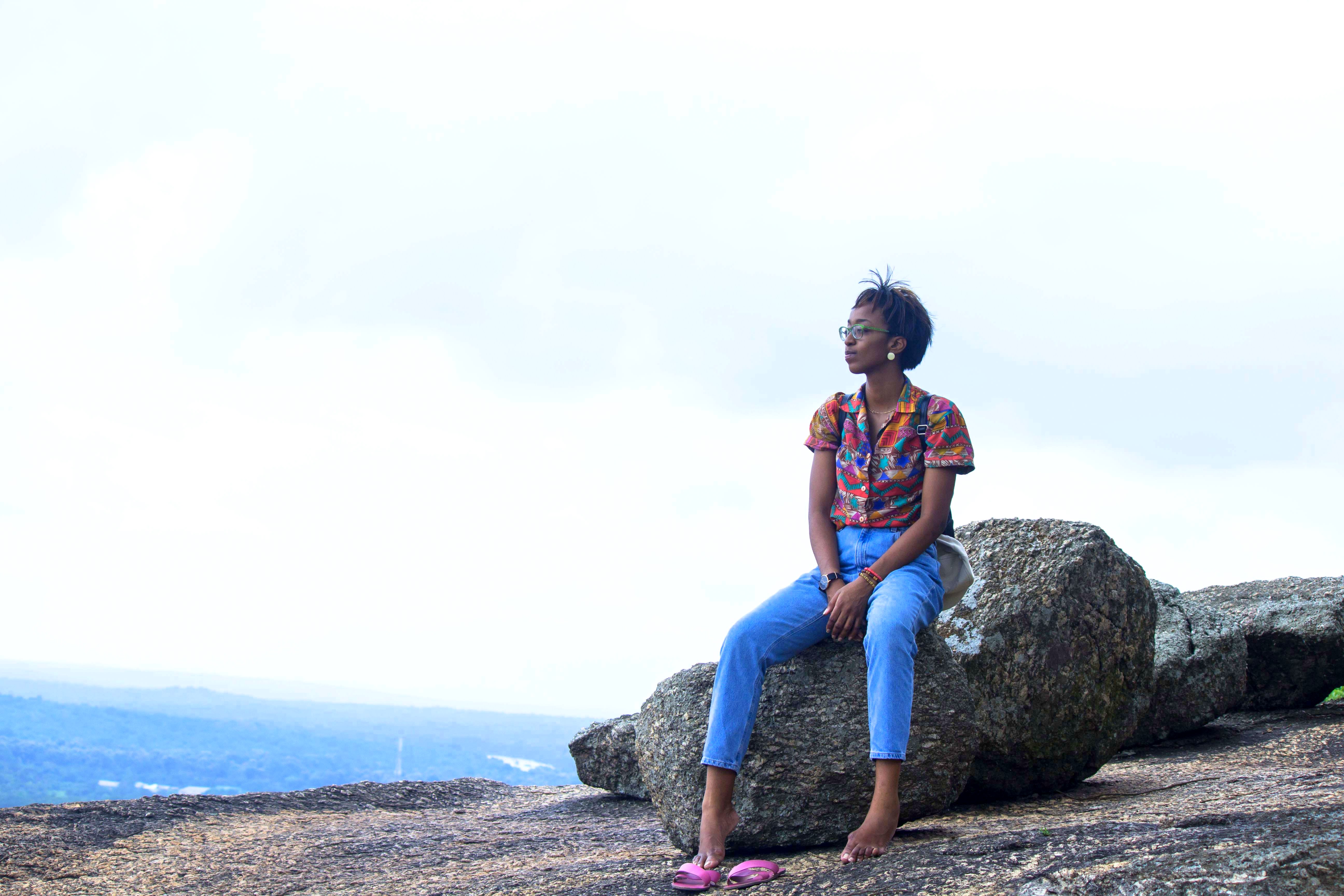 Blogger Cassie Daves sitting on a rock at the olumo rock, places to visit in abeokuta