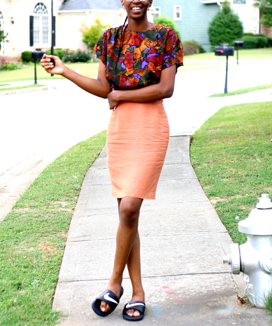Nigerian fashion blogger Cassie Daves in a profile shot wearing a bright coloured prints top, orange skirt and nike slides