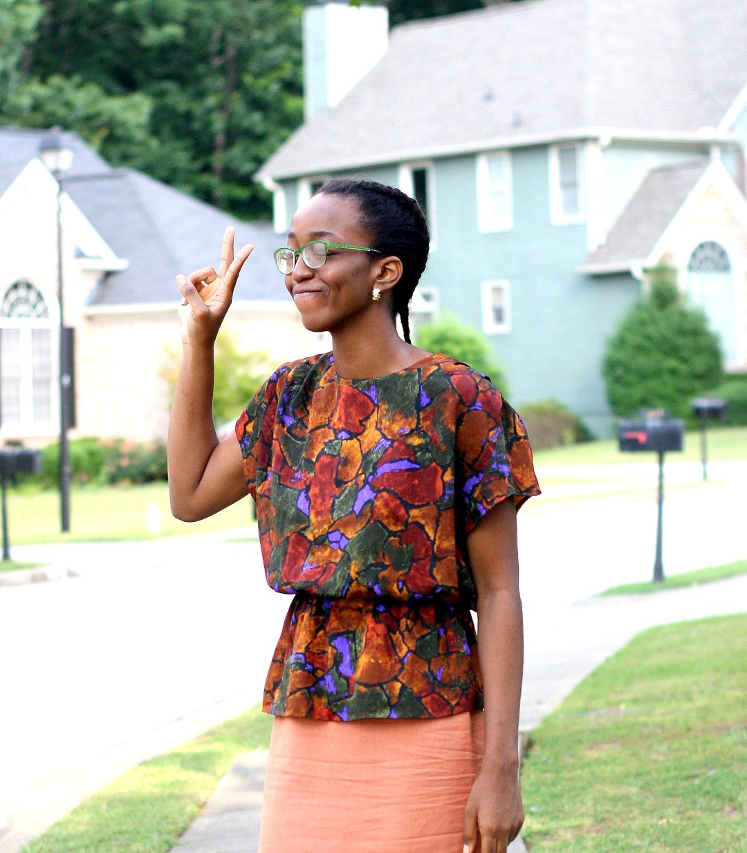 Going back to the basics - Nigerian fashion blogger Cassie Daves in a profile shot wearing a bright coloured peplum prints top and orange skirt 