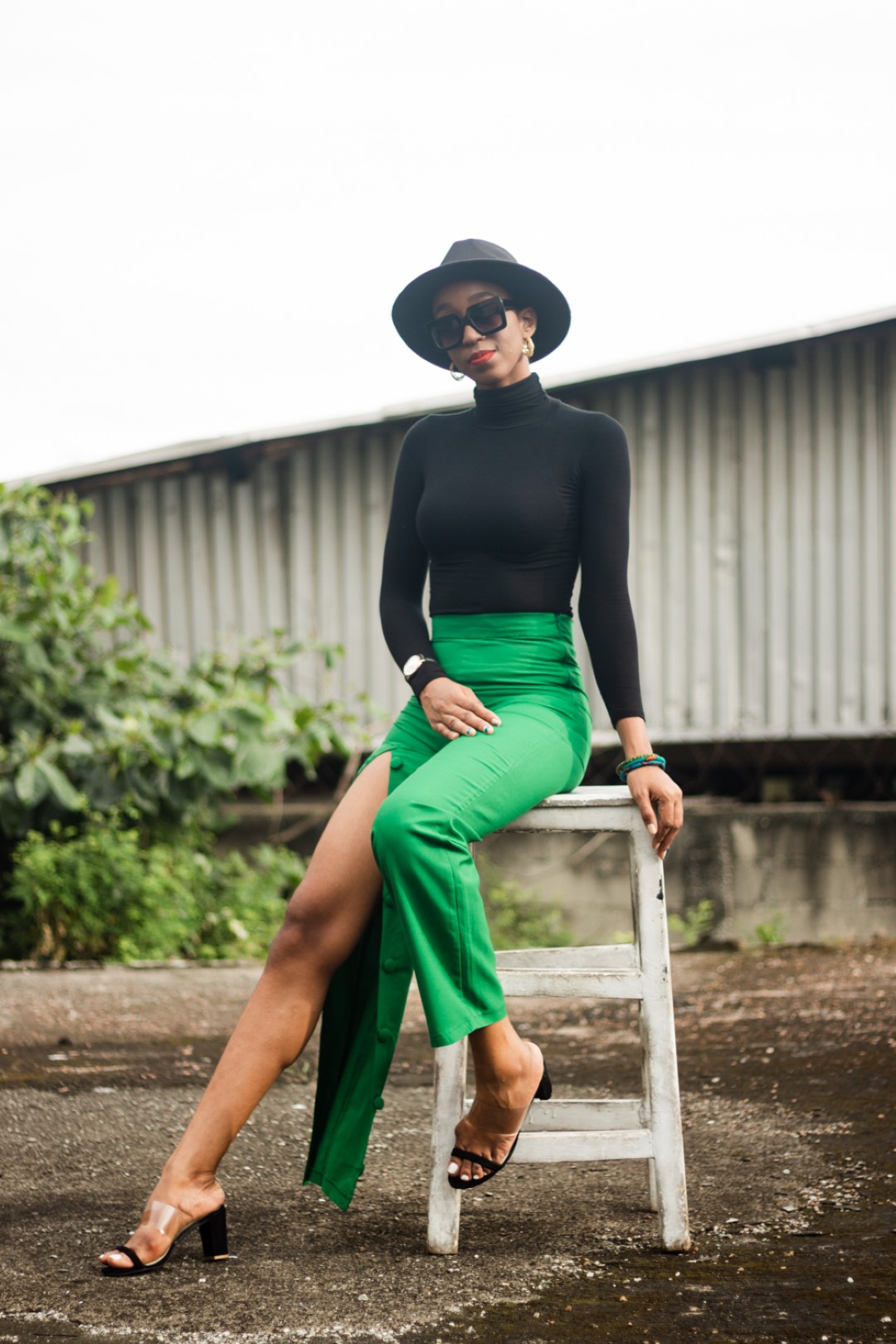 Cassie daves in a fedora hat and black turtle neck top and green pants from wawooh hq