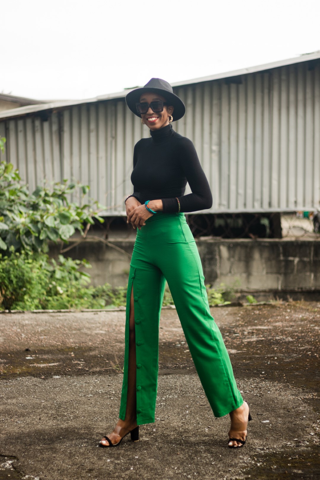 Cassie daves in a fedora hat and black turtle neck top and green pants from wawooh hq