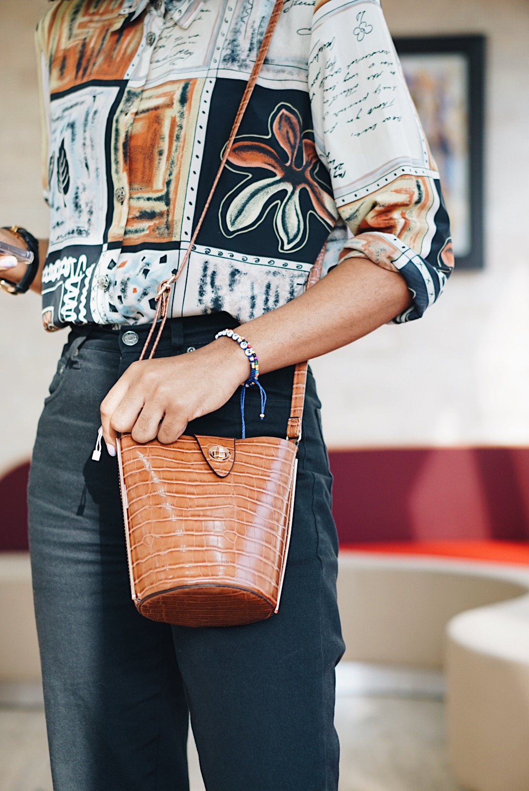 Cassie Daves wearing a vintage print shirt and brown mini bucket bag