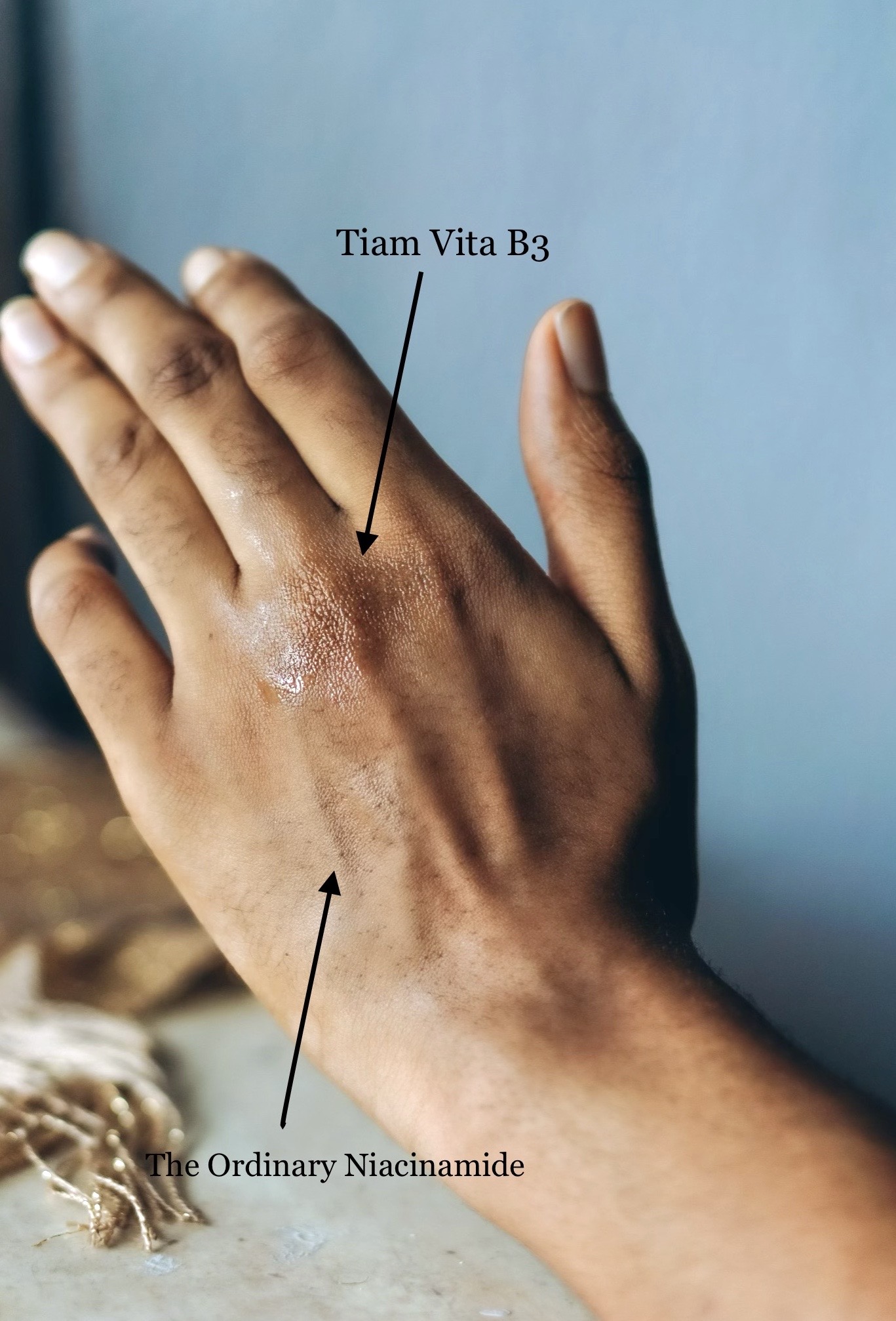 Picture of the back of Cassie Daves hand with a drop of both the tiam vita b3 source vs the ordinary niacinamide serum