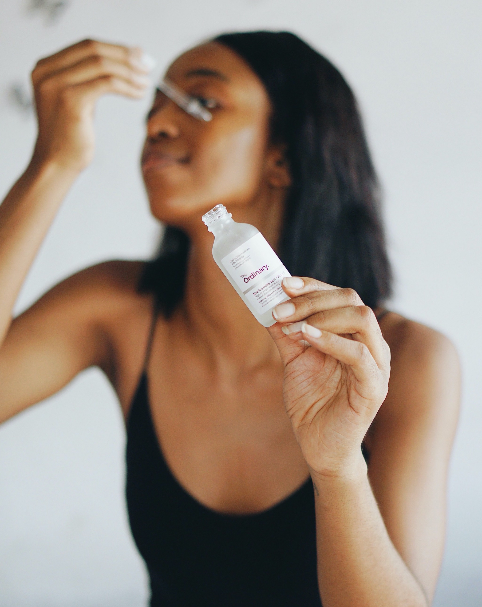 Blogger Cassie Daves holding the dropper and bottle of the ordinary niacinamide serum