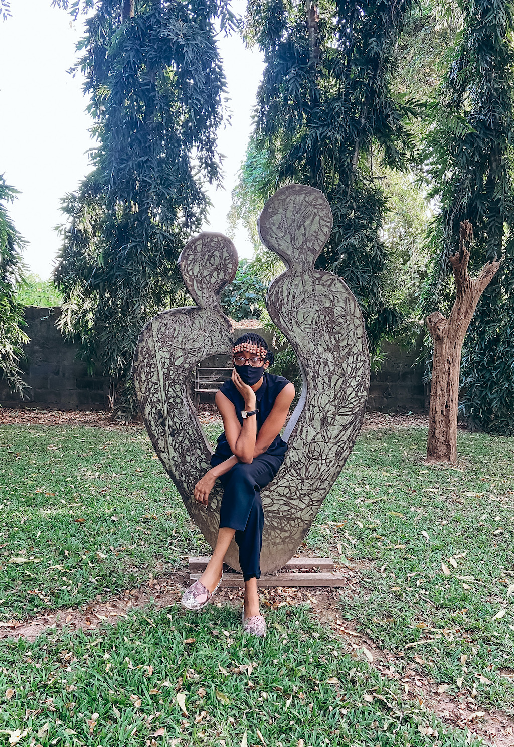 Cassie daves posing with a bronze figure at the Garden at nike guesthouse osogbo