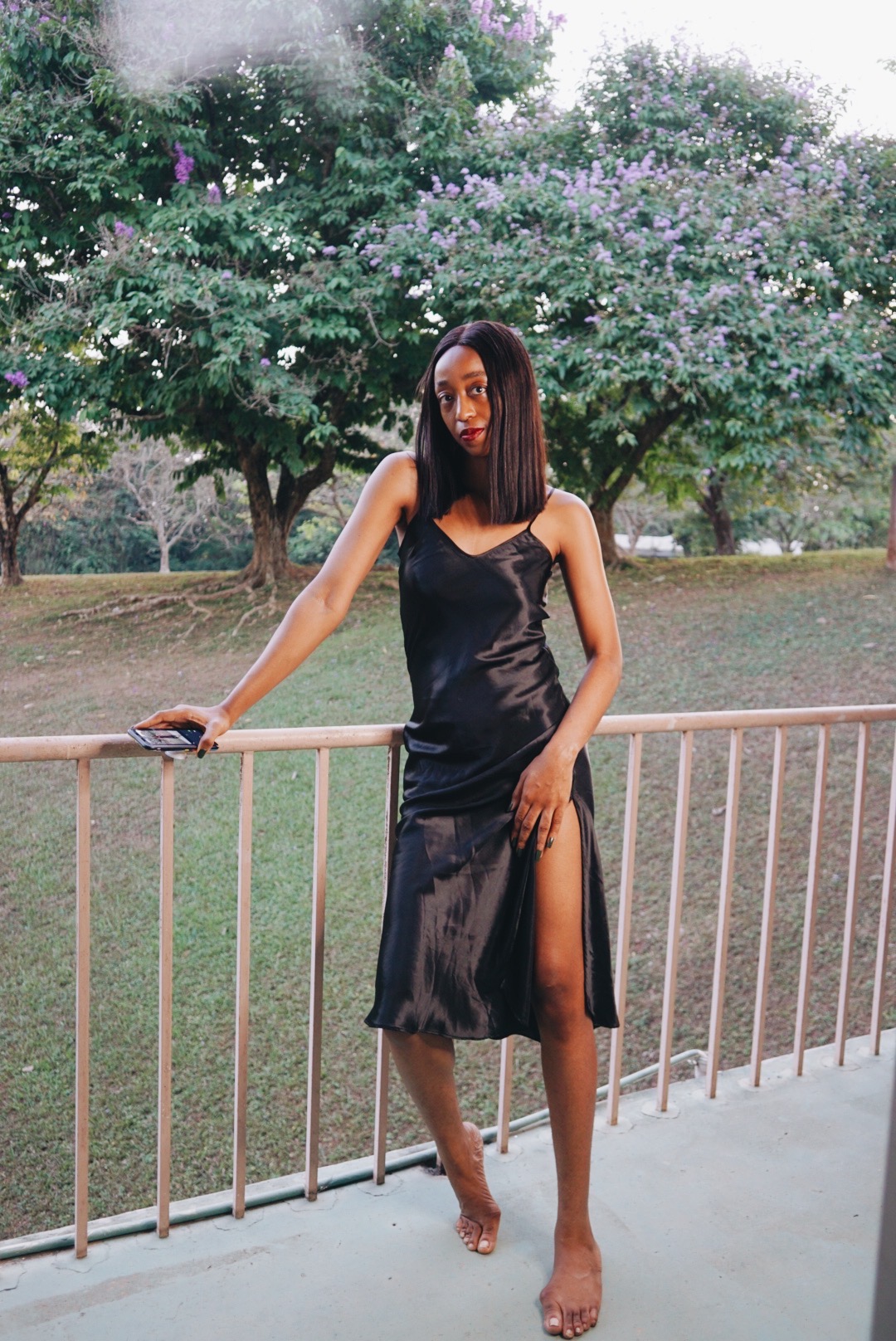 Cassie Daves wearing a black slip dress at a balcony