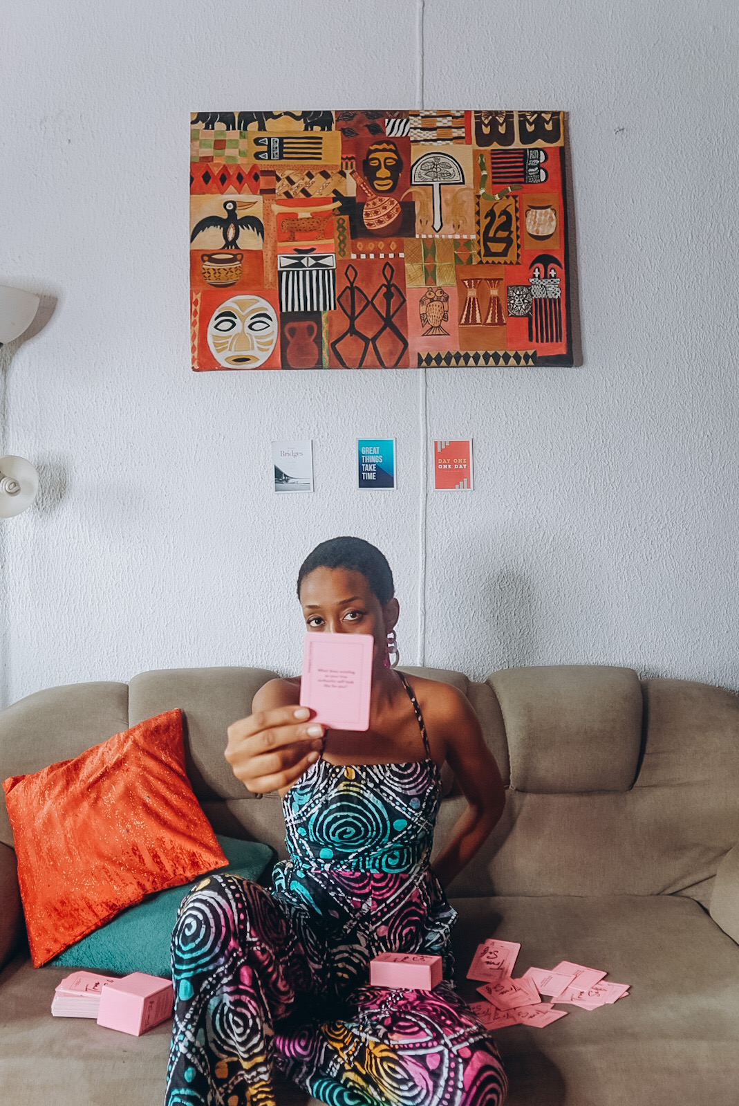 Nigerian blogger Cassie daves sitting on a couch with cards spread out, and holding up a true self reflection cards