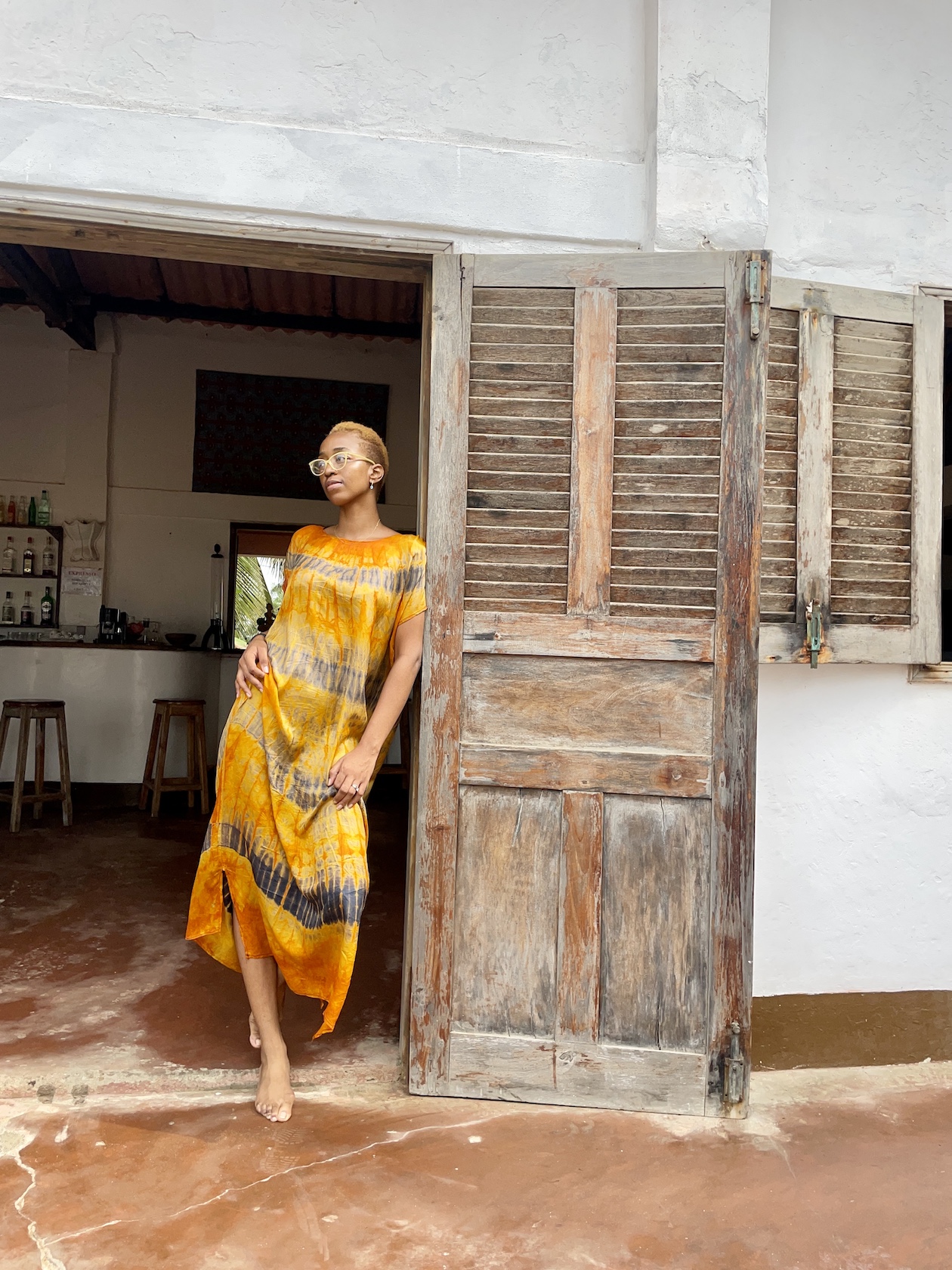 Nigerian blogger Cassie Daves leaning on the rustic doors of Auberge de grandpopo review